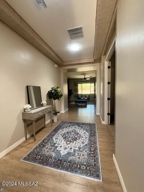 corridor featuring hardwood / wood-style floors and a tray ceiling