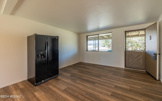 unfurnished bedroom featuring black fridge with ice dispenser and dark hardwood / wood-style floors