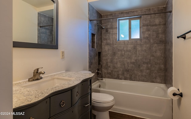 full bathroom featuring vanity with extensive cabinet space, tiled shower / bath, and toilet