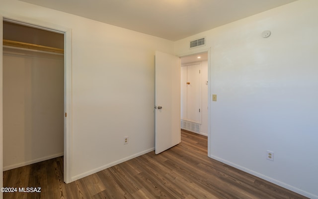 unfurnished bedroom featuring a closet and dark hardwood / wood-style floors