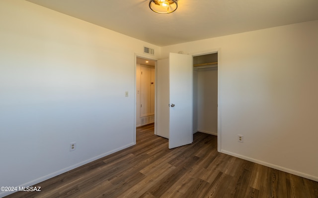 unfurnished bedroom featuring a closet and dark wood-type flooring