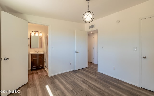 unfurnished bedroom with dark hardwood / wood-style floors, sink, and ensuite bathroom