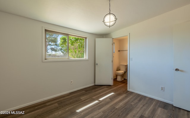 unfurnished bedroom featuring ensuite bath and dark hardwood / wood-style flooring