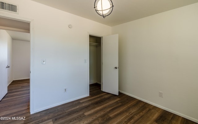 unfurnished bedroom with a closet and dark hardwood / wood-style flooring