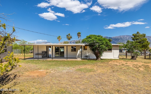 rear view of house featuring a mountain view and a lawn