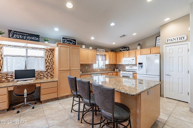 kitchen with white appliances, backsplash, sink, light stone counters, and a kitchen island