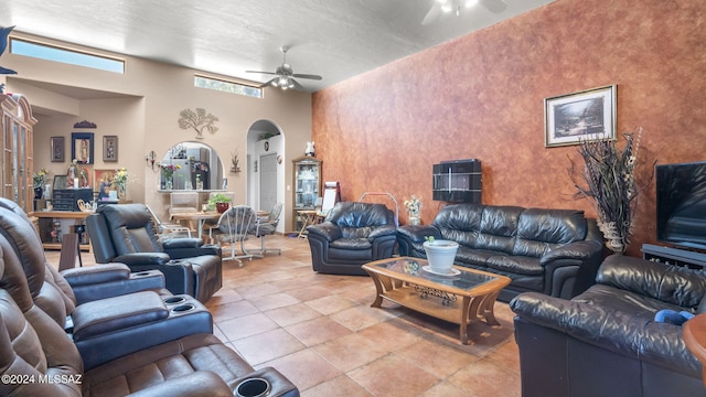 tiled living room featuring ceiling fan, a high ceiling, and a textured ceiling