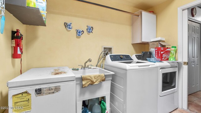 clothes washing area featuring washer hookup, cabinets, light tile floors, and washer and dryer