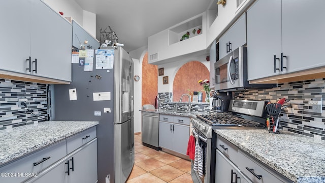 kitchen with light tile floors, sink, tasteful backsplash, gray cabinetry, and stainless steel appliances