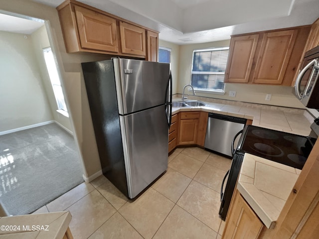 kitchen featuring appliances with stainless steel finishes, tile counters, a wealth of natural light, and light colored carpet