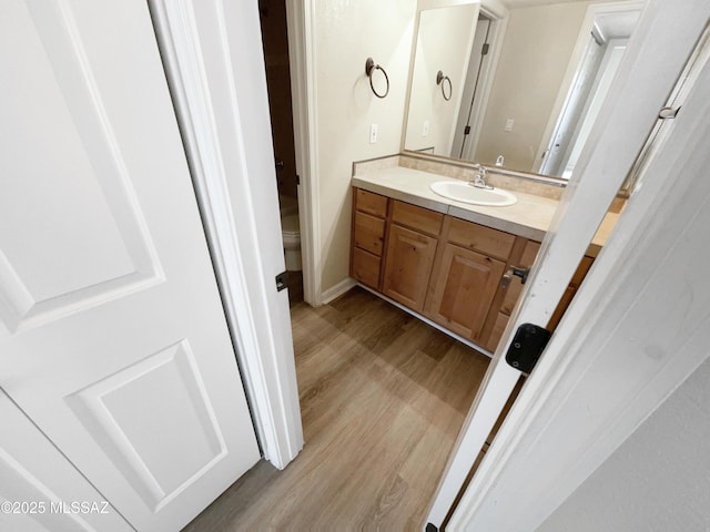 bathroom with wood-type flooring, toilet, and vanity