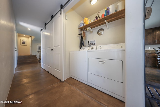 clothes washing area featuring washer hookup, a barn door, and washer and dryer