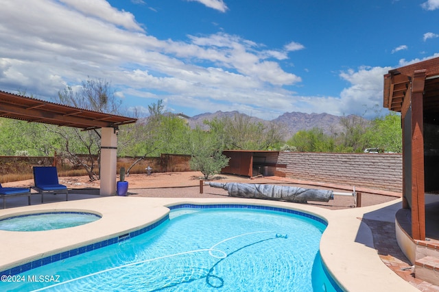 view of swimming pool with a patio area, a mountain view, and an in ground hot tub