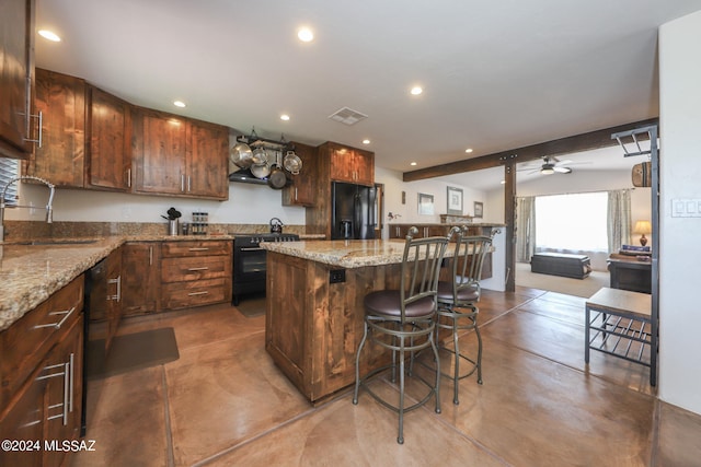 kitchen featuring black fridge, a kitchen island, ceiling fan, range, and sink