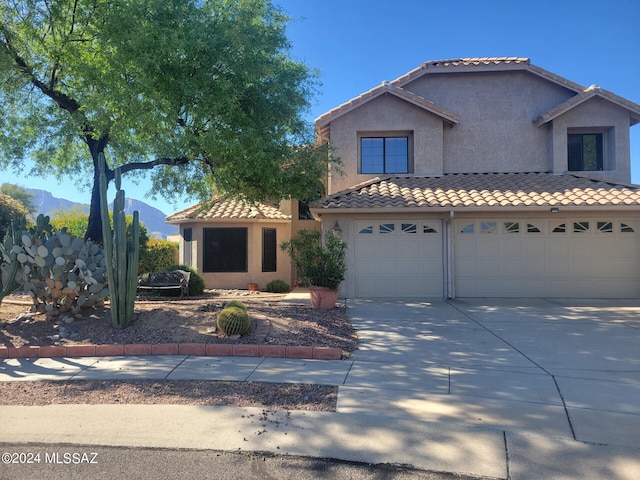 view of front of property with a tiled roof, concrete driveway, and stucco siding