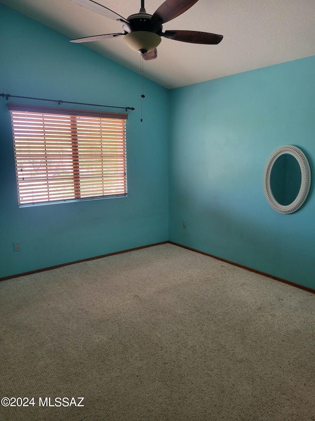 unfurnished room with carpet floors, baseboards, vaulted ceiling, and a ceiling fan