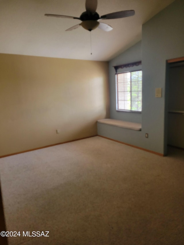 spare room featuring carpet, ceiling fan, lofted ceiling, and baseboards