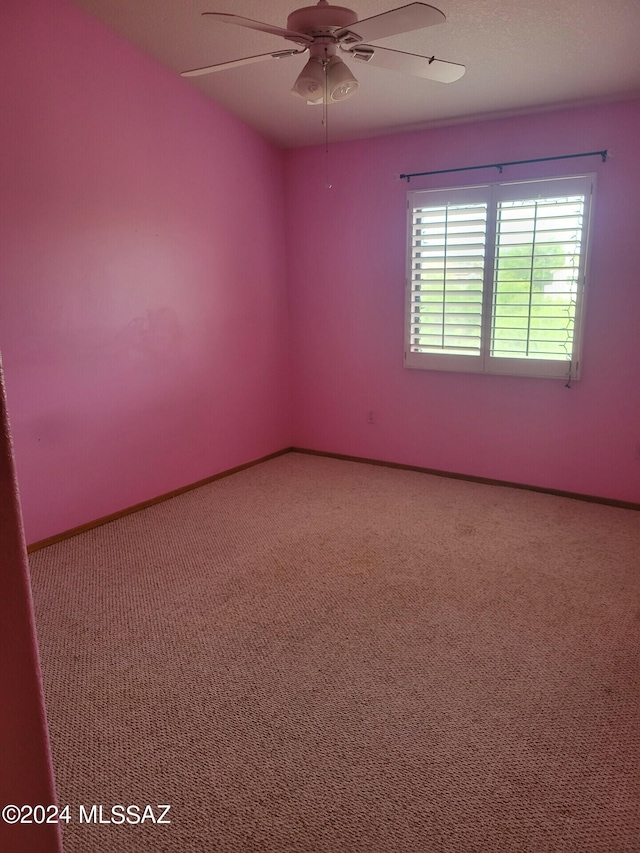 carpeted empty room featuring baseboards and a ceiling fan