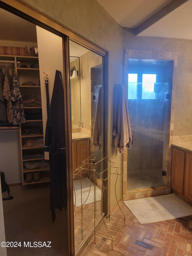 full bathroom featuring a stall shower, a spacious closet, and vanity