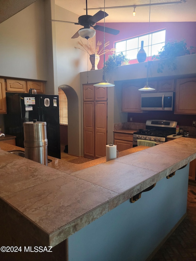 kitchen with stainless steel appliances, high vaulted ceiling, and a kitchen bar