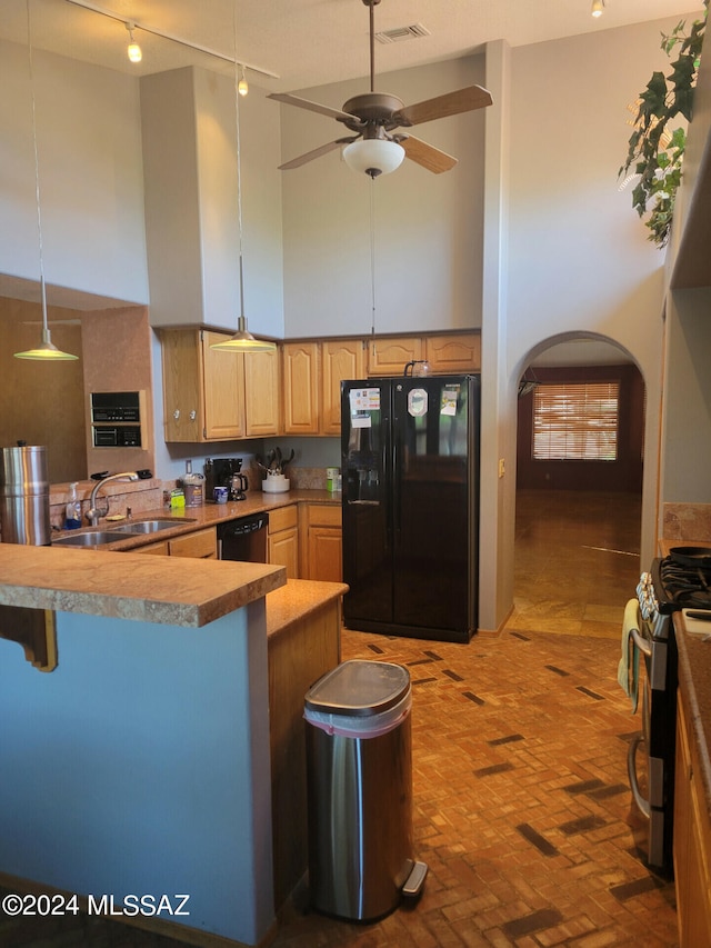 kitchen featuring a high ceiling, a sink, visible vents, black fridge, and stainless steel range with gas stovetop