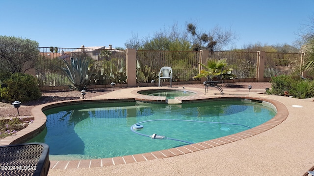 view of pool featuring a pool with connected hot tub and fence