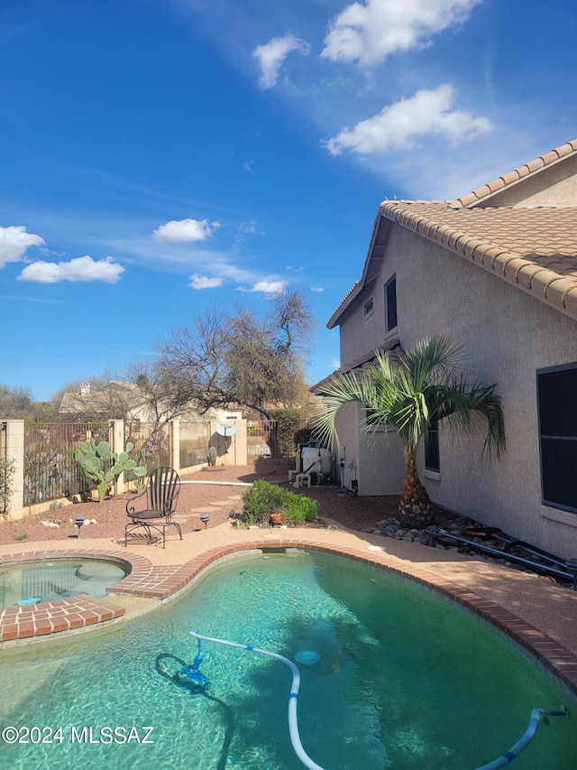 view of pool featuring fence, a fenced in pool, and an in ground hot tub