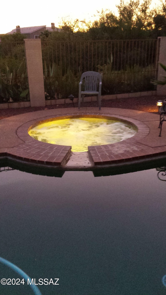 view of pool featuring a pool with connected hot tub and fence