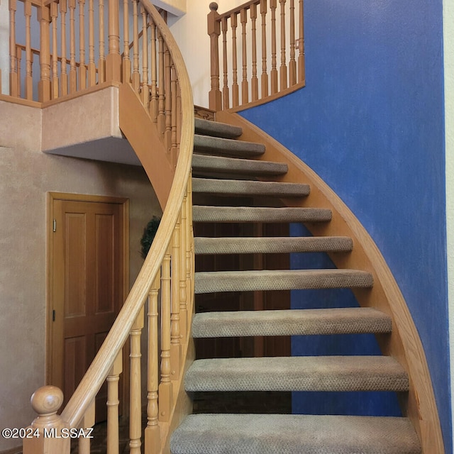 staircase featuring a high ceiling and baseboards