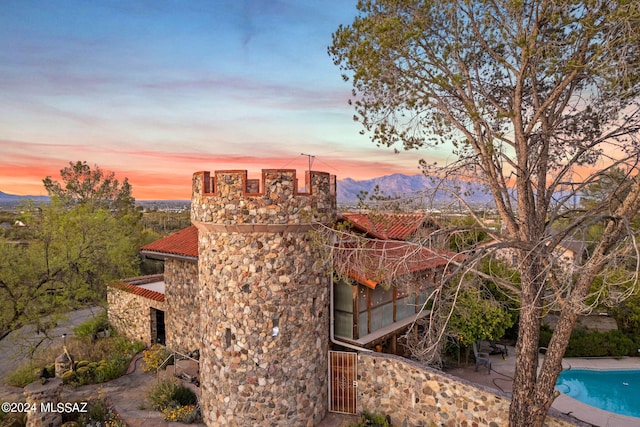 property exterior at dusk with a mountain view and a patio