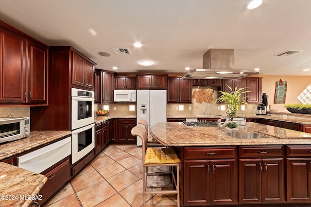 kitchen with a large island, island range hood, white appliances, and light stone countertops