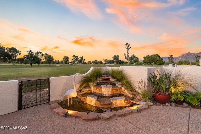 patio terrace at dusk featuring a yard and a mountain view