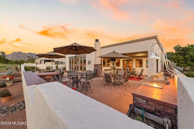 patio terrace at dusk with area for grilling and a mountain view