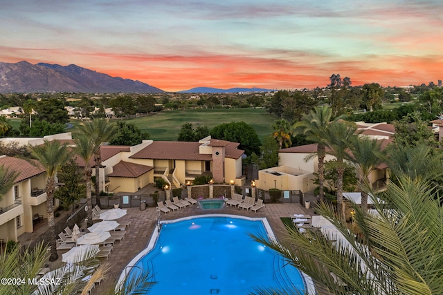 pool at dusk with a patio area and a mountain view