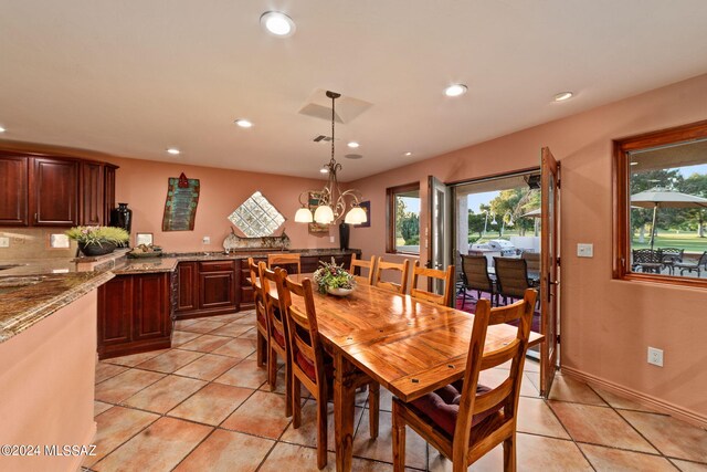 dining space with a wealth of natural light, light tile patterned floors, and an inviting chandelier