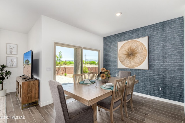 dining area with dark wood-type flooring and tile walls