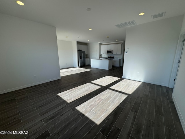 unfurnished living room featuring dark hardwood / wood-style floors and sink