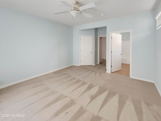 unfurnished bedroom with ensuite bath, light colored carpet, and ceiling fan