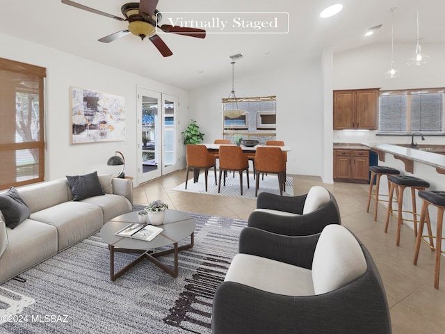 tiled living room with ceiling fan, a wealth of natural light, vaulted ceiling, and french doors