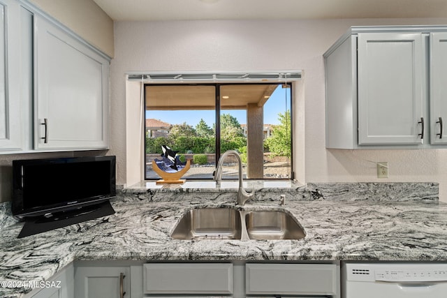 kitchen with dishwasher, light stone countertops, and sink