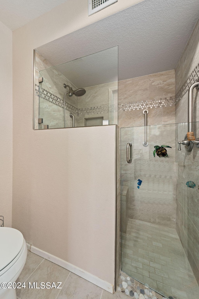 bathroom with toilet, a textured ceiling, tile patterned floors, and walk in shower