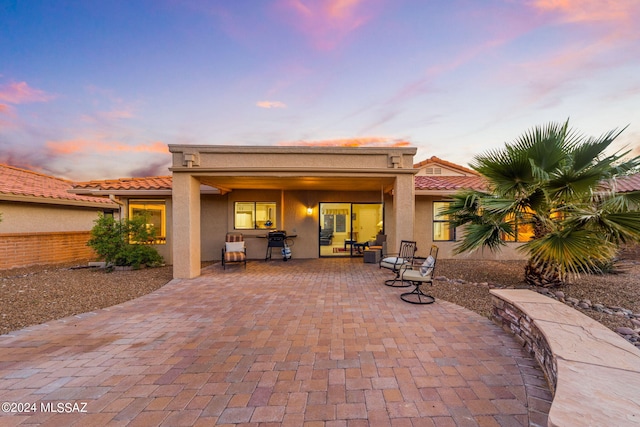 back house at dusk featuring a patio