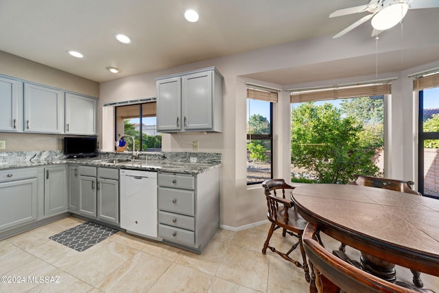 kitchen featuring light stone countertops, dishwasher, plenty of natural light, and sink