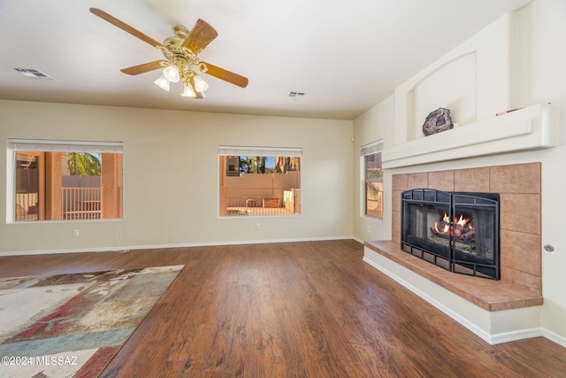 living room featuring dark hardwood / wood-style floors, ceiling fan, and a tile fireplace