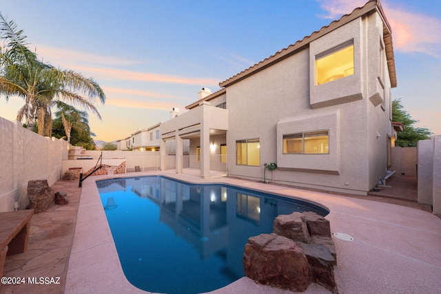 pool at dusk with a patio area