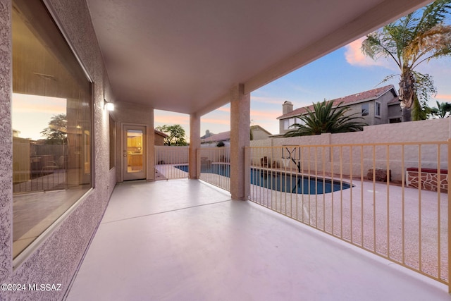 patio terrace at dusk featuring a fenced in pool