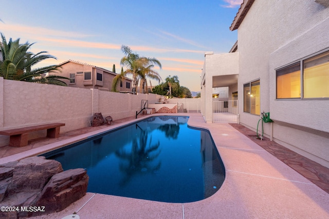 pool at dusk with a patio area