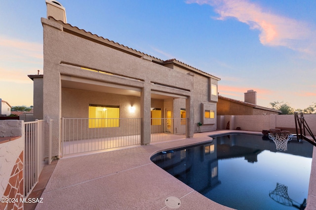 pool at dusk with a patio area