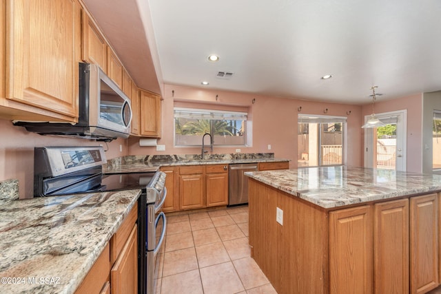 kitchen with appliances with stainless steel finishes, light tile flooring, a kitchen island, and plenty of natural light