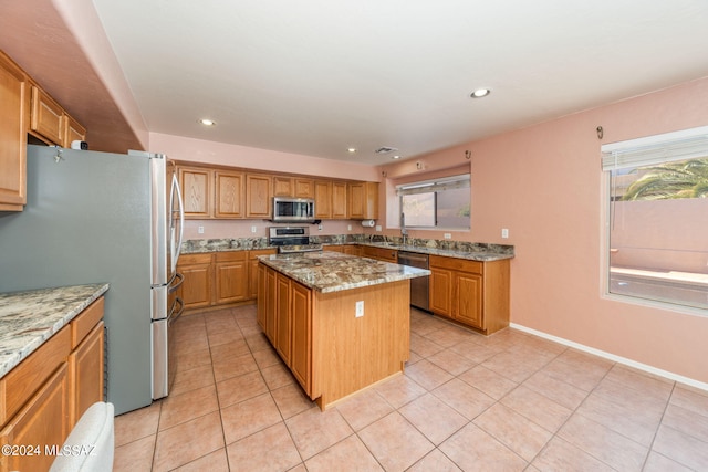 kitchen featuring light stone counters, appliances with stainless steel finishes, light tile floors, and a kitchen island